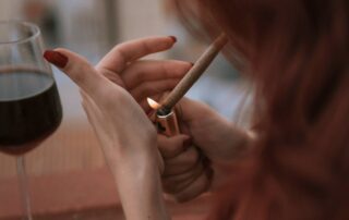 Mulher acendendo um cigarro de maconha, ilustrando debate sobre como a maconha pode desencadear esquizofrenia.