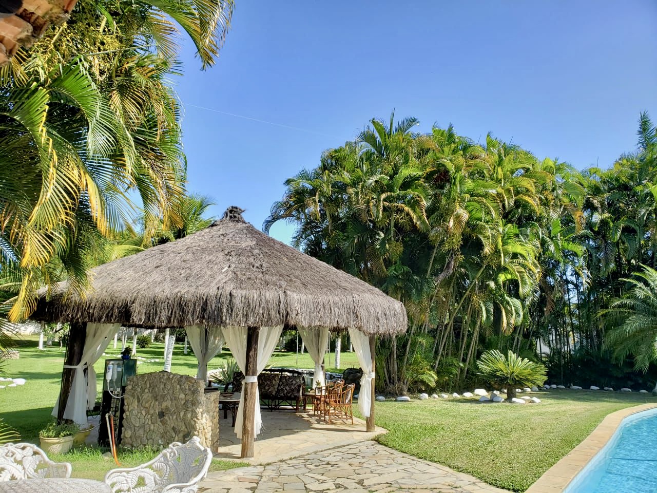 Área externa da clínica psiquiátrica Instituto Aron RJ com quiosque de sapê, piscina e jardim, referência em internação psiquiátrica de alto padrão.